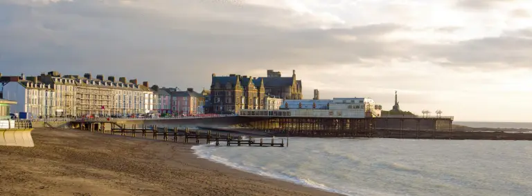 Glan y môr a’r pier yn Aberystwyth ar fachlud haul